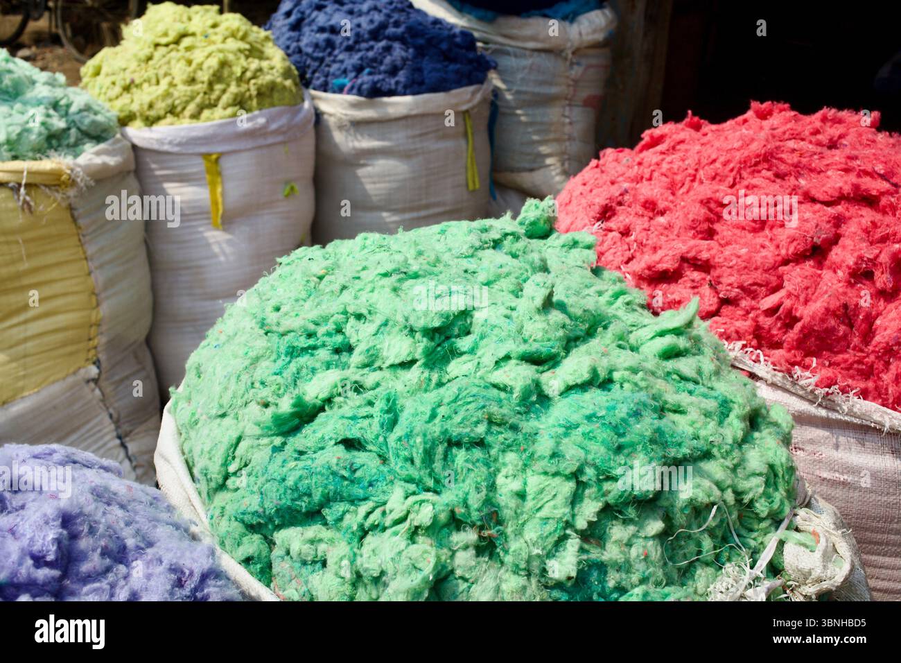 Hell gefärbte Textilfasern in Schüttsäcken, Kurigram, Bangladesch, die auf Verarbeitung oder Weiterverkauf in der informellen Recyclingwirtschaft warten. Stockfoto