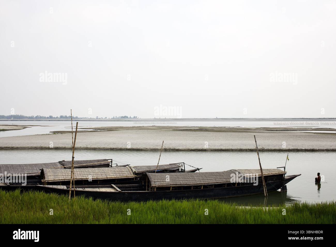 Traditionelle Boote mit Bambusdach, die entlang des Brahmaputra River in Chilmari, Kurigram, ankern, während Sandbänke in der Trockenzeit entstehen. Stockfoto