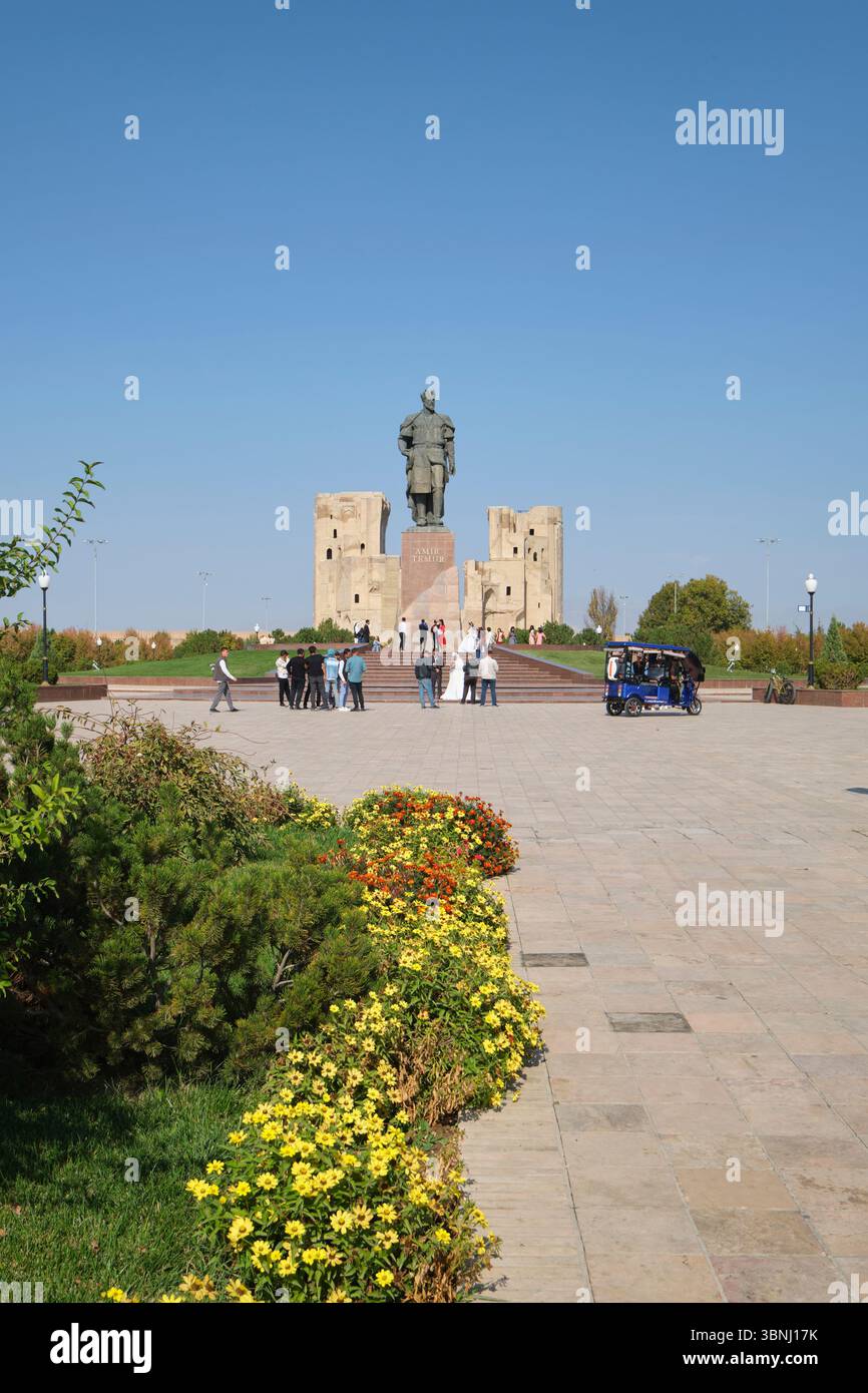 Eine typische Szene einer Hochzeitsfeier, die Fotos macht. An der riesigen Skulptur Amir Timur, Statue des Führers in Shahrisabz, Usbekistan. Stockfoto
