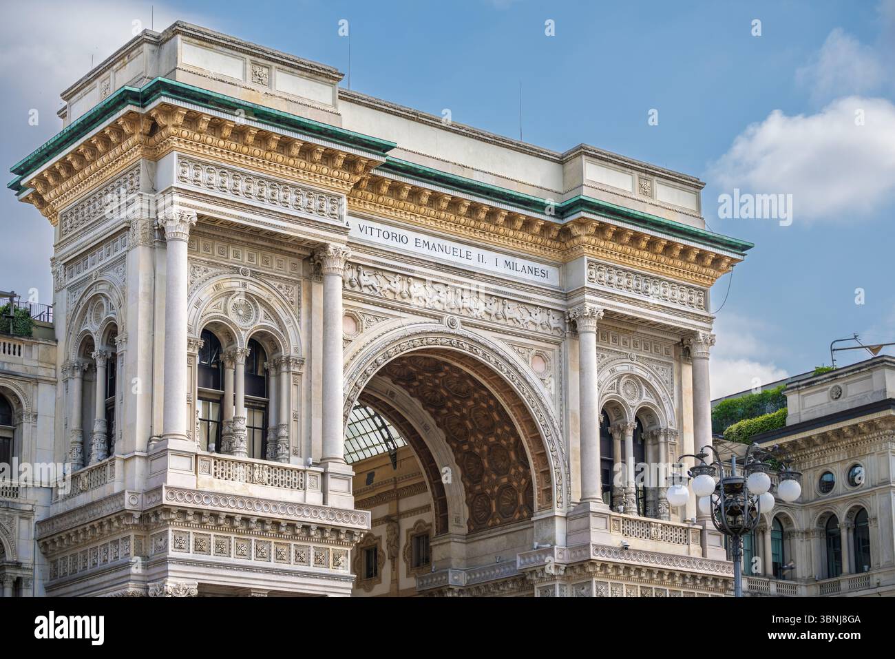 Mailand, Italien. Juni 2025. Der monumentale Eingangsbogen der Galleria Vittorio Emanuele II mit kunstvoller neoklassizistischer Dekoration unter sonnigem Himmel Stockfoto