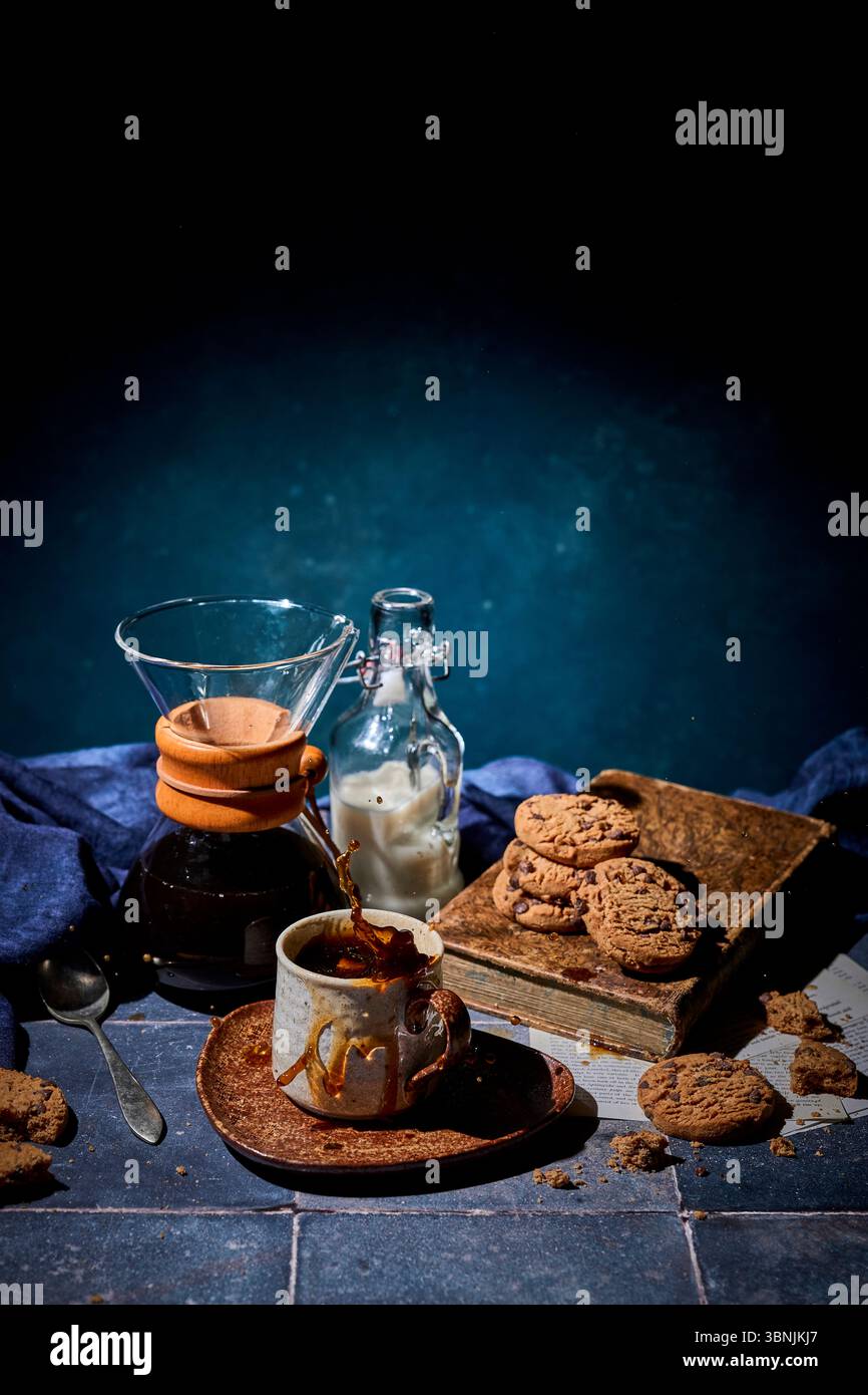 Ein gemütliches Ambiente mit einem Spritzer frischen Kaffee in einer Keramikbecher, einem Stapel Schokoladenkekse und einer Flasche Milch in der Nähe, die Wärme und Wärme wecken Stockfoto