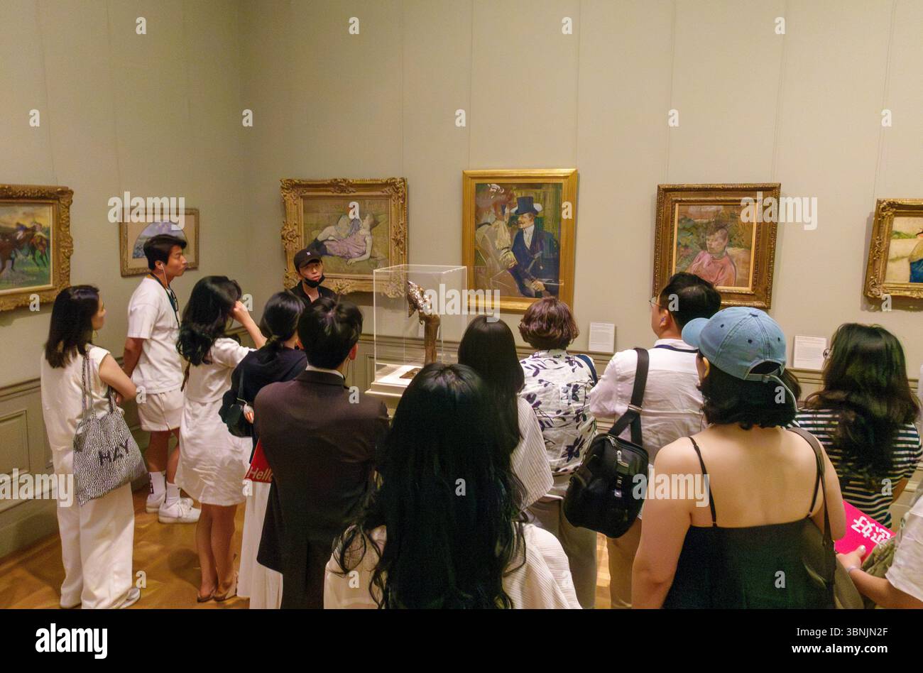 Japanische Besucher hören einem Reiseleiter in einem Galeriergespräch zu, Metropolitan Museum of Art, New York City, USA Stockfoto