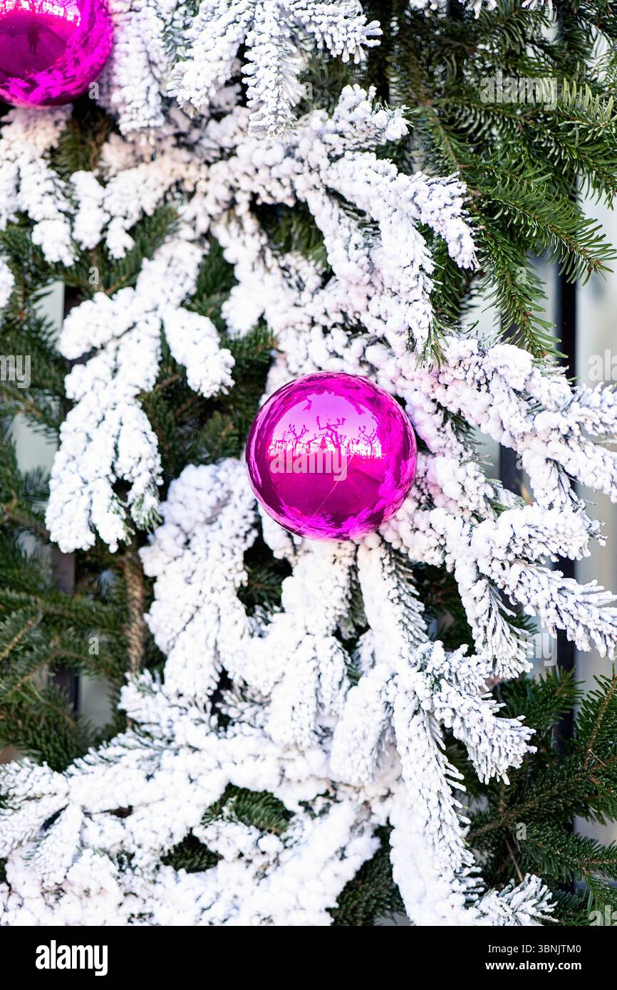 Ein wunderschöner Weihnachtskranz mit leuchtenden rosafarbenen Kugeln und mattierten Zweigen. Die Nadeln aus grüner Kiefer stehen im Kontrast zum schneebedeckten Effekt und erzeugen einen Stockfoto
