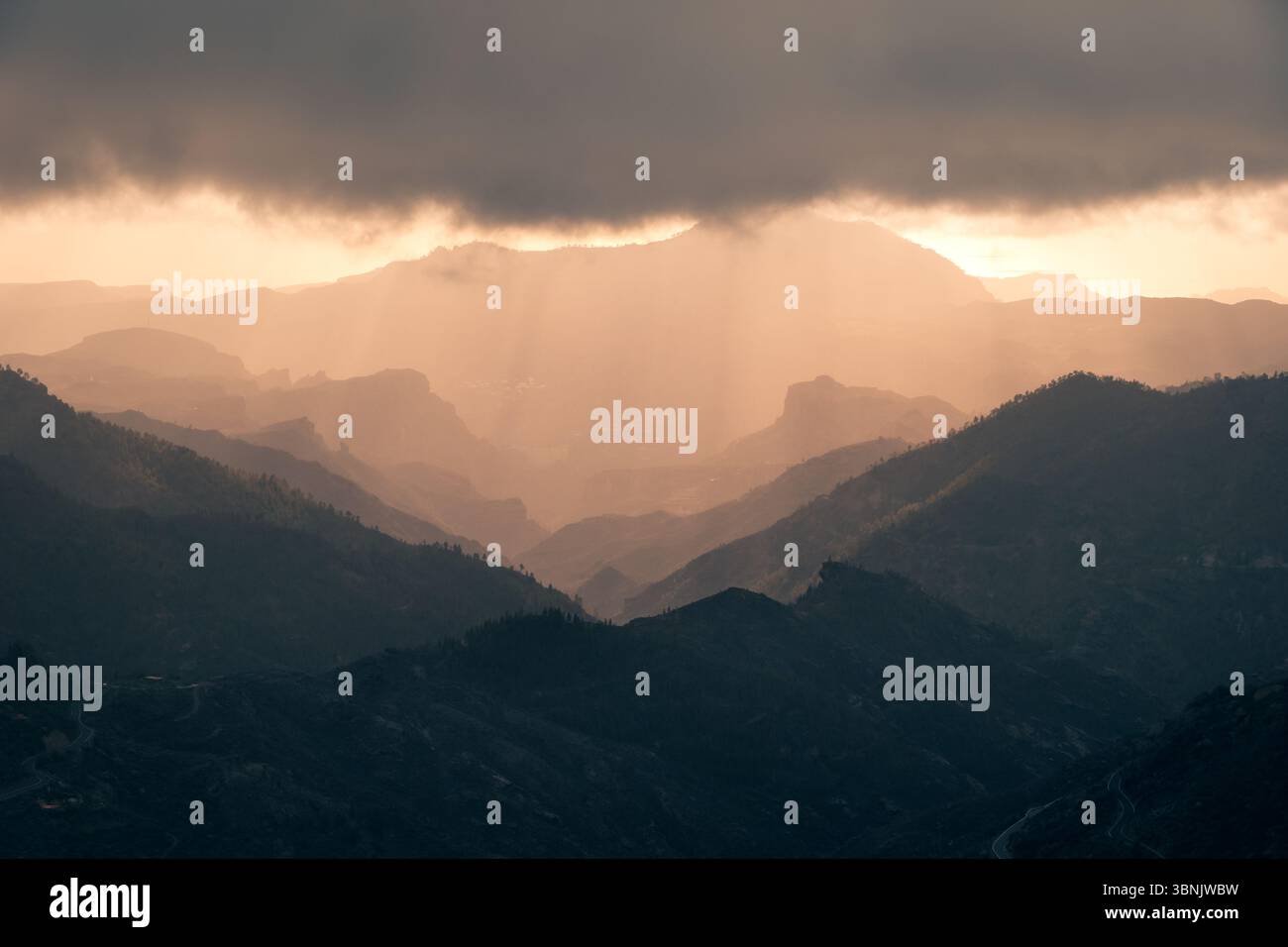 Das Bild zeigt einen bewölkten Tag in den Bergregionen von Gran Canaria, Spanien. Schichten von schroffen Gipfeln bilden eine Silhouette gegen die weichen, diffusen s Stockfoto