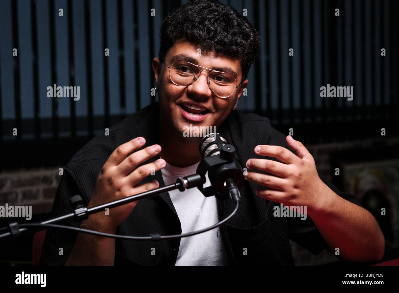 Ein souveräner Podcast-Host, der leidenschaftlich eine Live-Session aufnimmt, und das mit einem professionellen Mikrofon. Die Umgebung spiegelt eine ansprechende Atmosphäre für wider Stockfoto