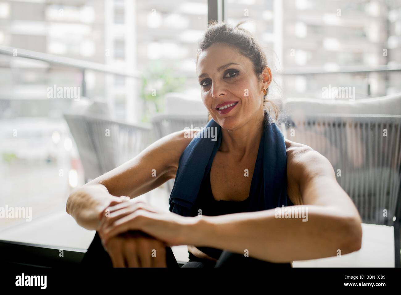 Eine entschlossene Frau macht eine Pause von ihrem Heimtraining und zeigt Ausdauer und Kraft. Das gemütliche Zuhause sorgt für zusätzlichen Komfort Stockfoto