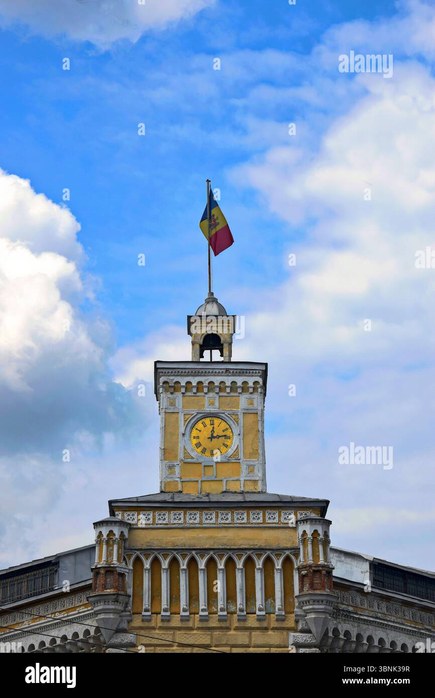 Moldauische Flagge ist auf dem Uhrenturm des alten Gemeindegebäudes auf wolkenbewölktem Himmel angebracht. Chisinau, Moldawien Stockfoto