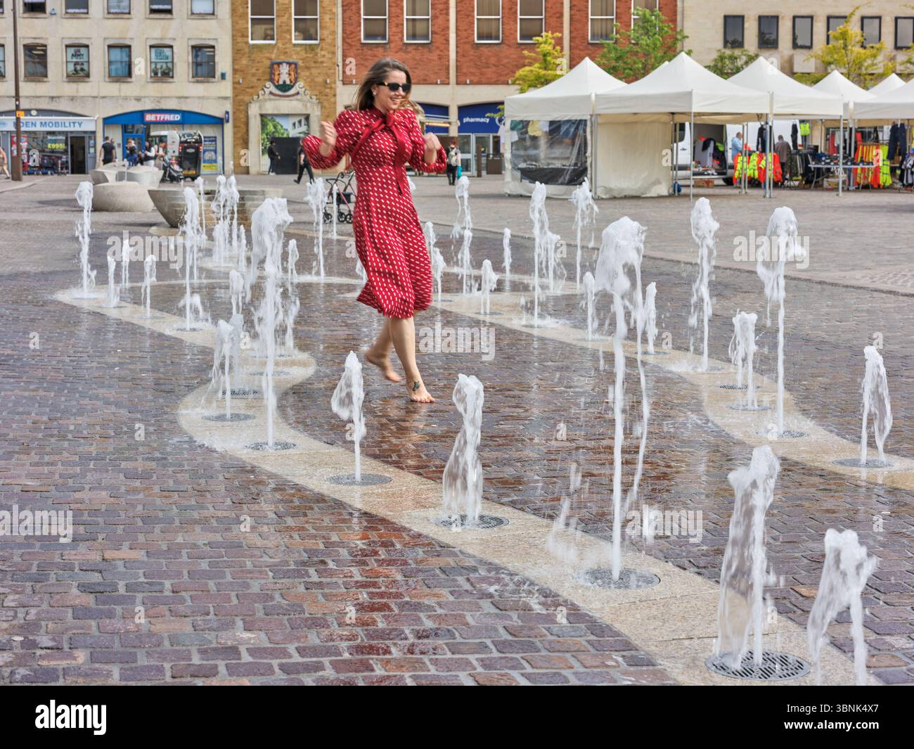 Frau fasziniert von den Wasserfontänen, Market Square, Northampton, England. Stockfoto