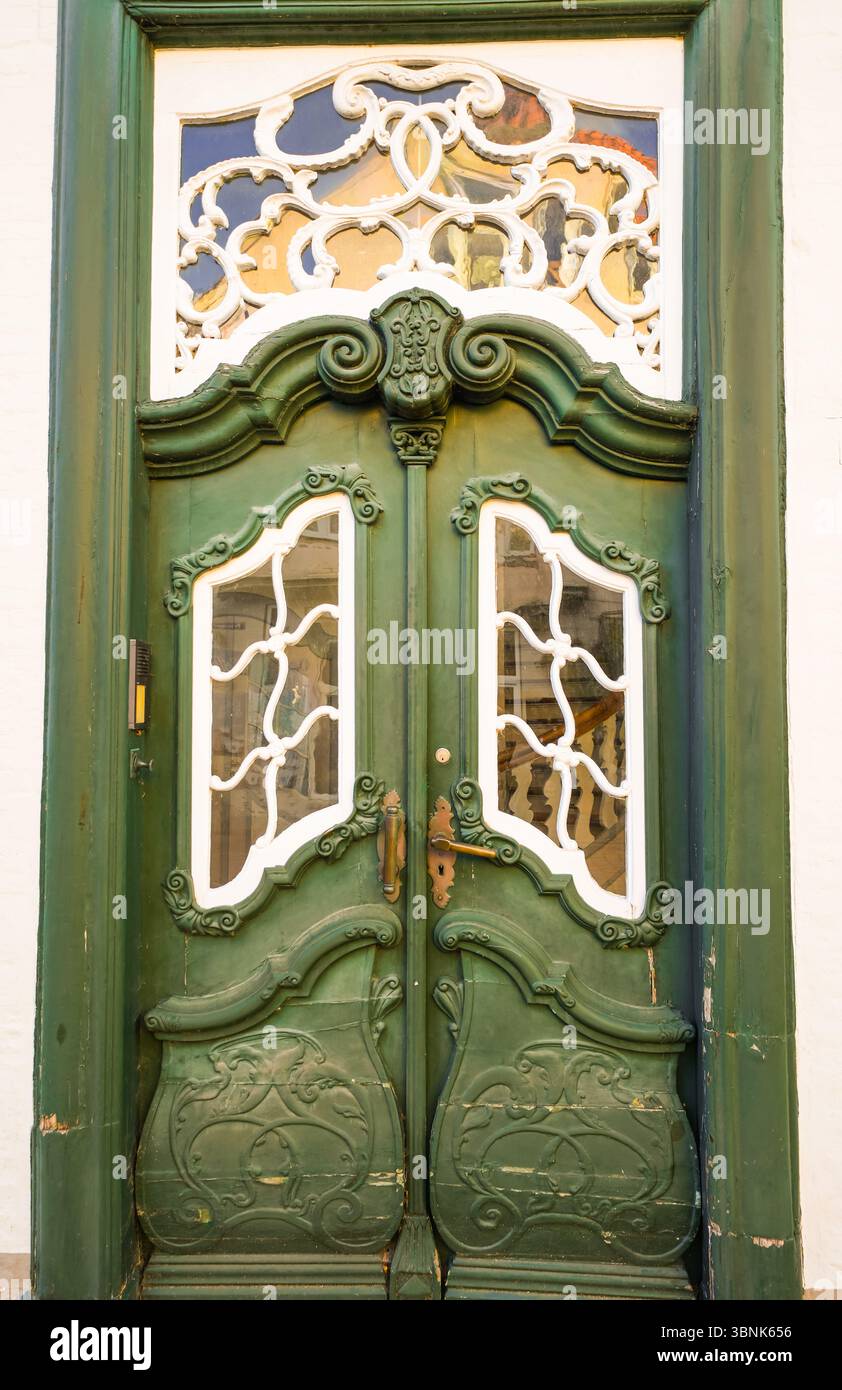 Alte Holztür mit Schnitzereien in Grün und weiß. Stockfoto