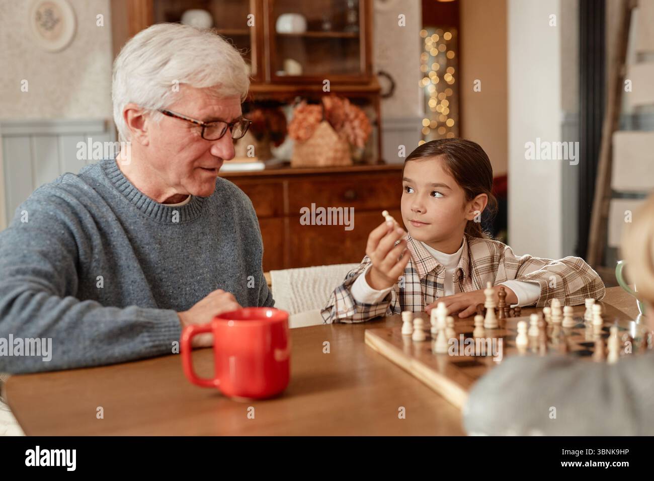 Senior-Kaukasier spielt Schach mit Enkeln in häuslicher Umgebung Stockfoto