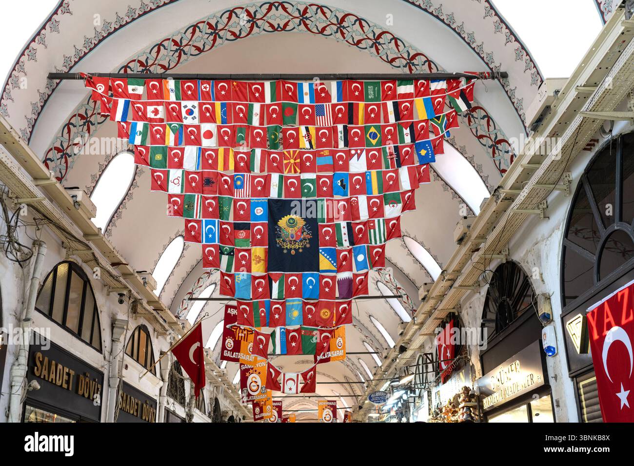 Eine Ausstellung von Weltflaggen um eine osmanische Flagge, die von der verzierten Decke im Inneren des Großen Basars hängt. Stockfoto