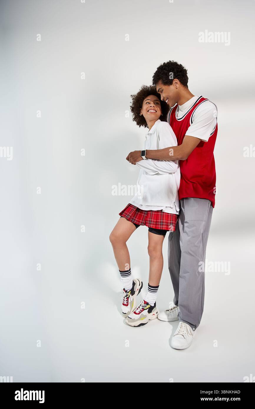 Liebevolles Paar, das modisch gekleidet ist, eine verspielte Umarmung genießt und gleichzeitig Erinnerungen schafft. Stockfoto