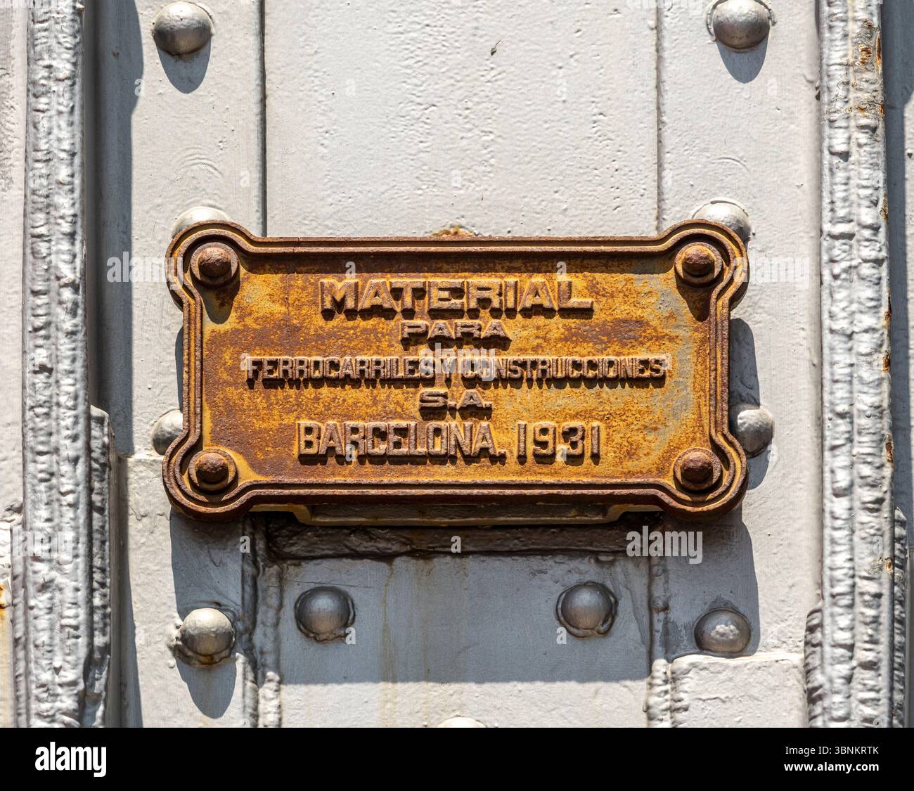 Eine alte, rostige Fabrikplatte aus dem Jahr 1931 auf einer genieteten Eisenkonstruktion in Barcelona. "Material para Ferrocarriles y Construcciones S.A." Spanien. Stockfoto
