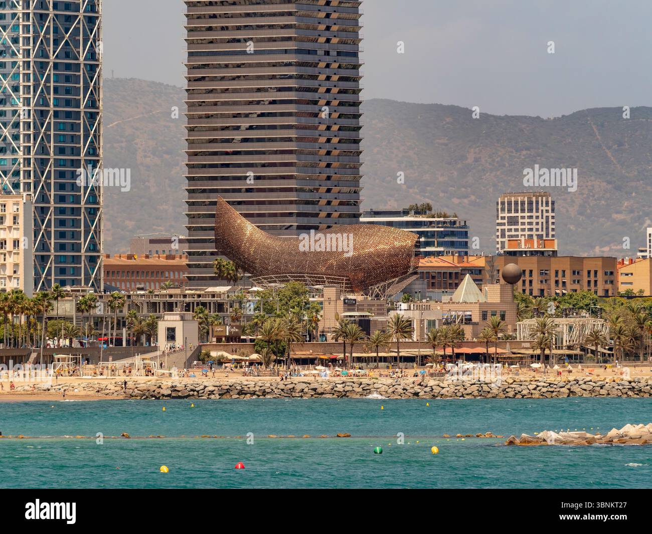 Die ikonische Skulptur „Peix“ (Fisch) von Frank Gehry im Hafen von Barcelona Olímpic mit dem Wolkenkratzer Hotel Arts im Hintergrund. Spanien. Stockfoto