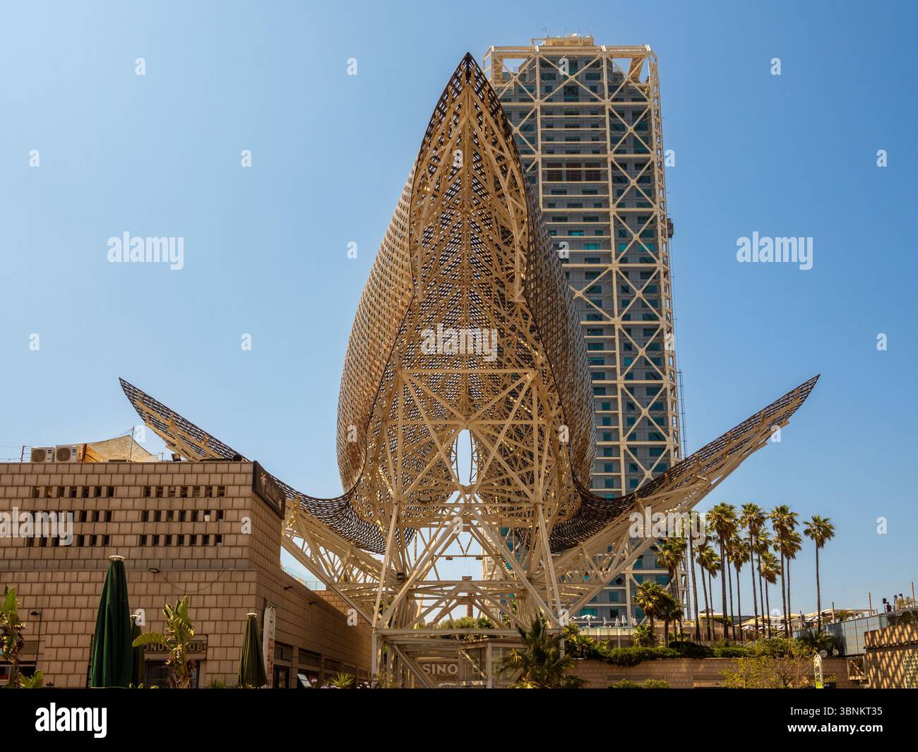 Frank Gehrys ikonische goldene Fischskulptur „El Peix“ in Port Olímpic mit dem Hotel Arts dahinter. Barcelona, Spanien. Stockfoto