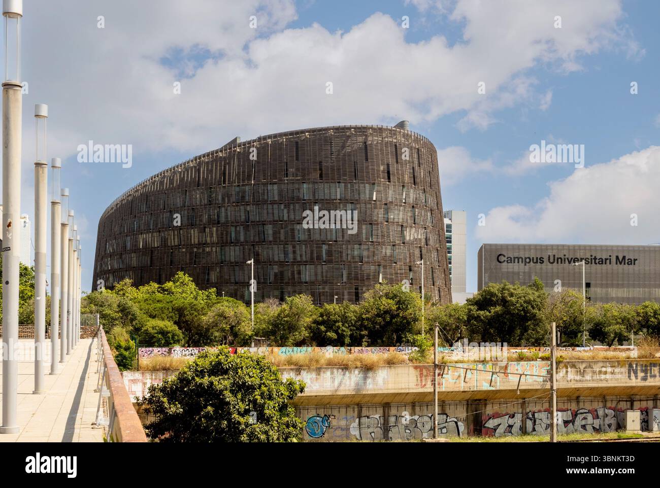 Das Gebäude des Barcelona Biomedical Research Park (PRBB) befindet sich neben dem Campus Universitari Mar mit Graffiti-bedeckten Wänden im Vordergrund Stockfoto