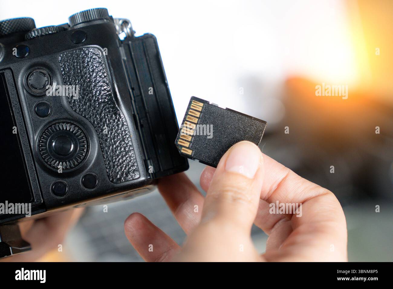 Nahaufnahme der Hand, die Speicherkarte aus der Kamera entfernt, symbolisiert den digitalen Workflow und die Bildspeicherung. Stockfoto