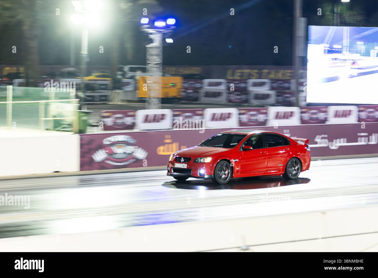 Motion Blur Drag Racing bei Nacht, bei dem Autos auf der Rennstrecke mit Zuschauern in der Nähe konkurrieren Stockfoto