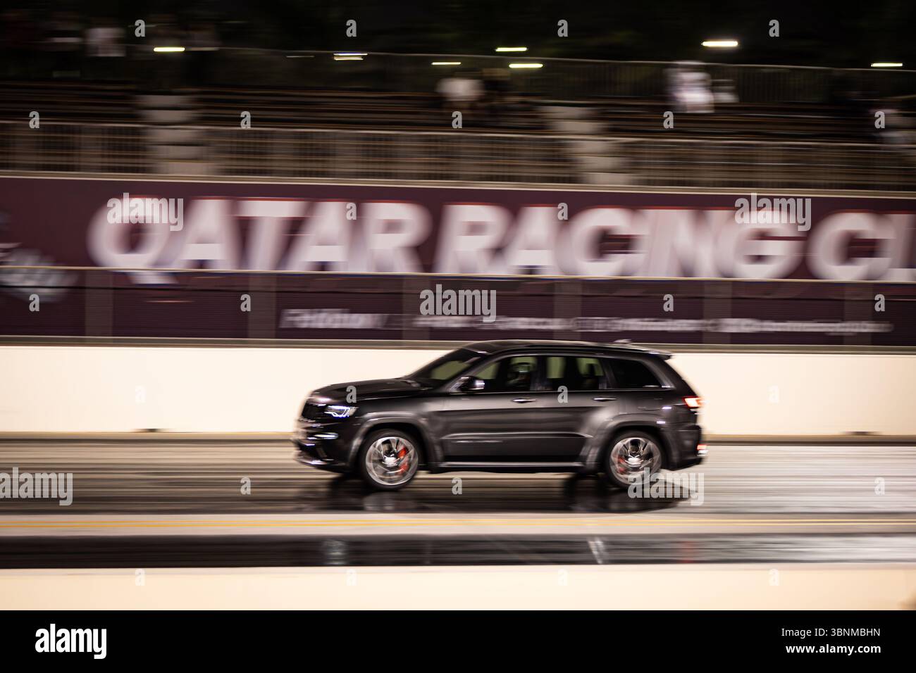 Motion Blur Drag Racing bei Nacht, bei dem Autos auf der Rennstrecke mit Zuschauern in der Nähe konkurrieren Stockfoto