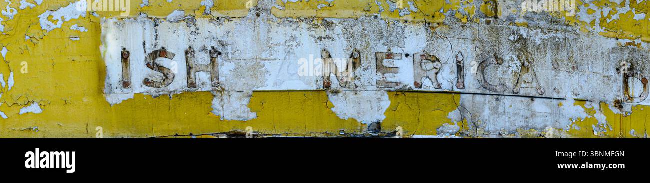 Nahaufnahme eines gelb-weißen Tankstellenschilds mit fehlenden Buchstaben und abblätternder Farbe. Stockfoto