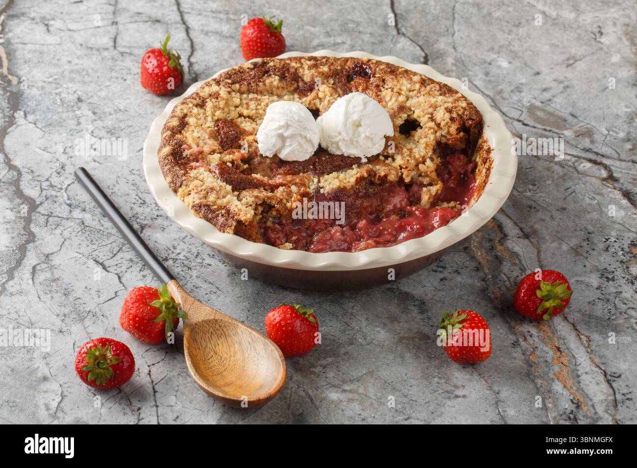 Sommer-Dessert Kakao-Erdbeere-Schuster mit Vanilleeis in der Backform auf dem Tisch. Horizontal Stockfoto
