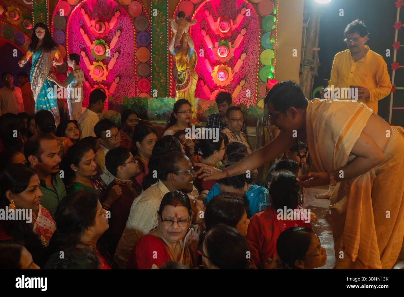 Howrah, Westbengalen, Indien, 3. Oktober 2022: Hindu purohit zeichnet tilak, heiliges Zeichen auf der Stirn von Hindu-Gläubigen, die Göttin Durga anbeten. Stockfoto