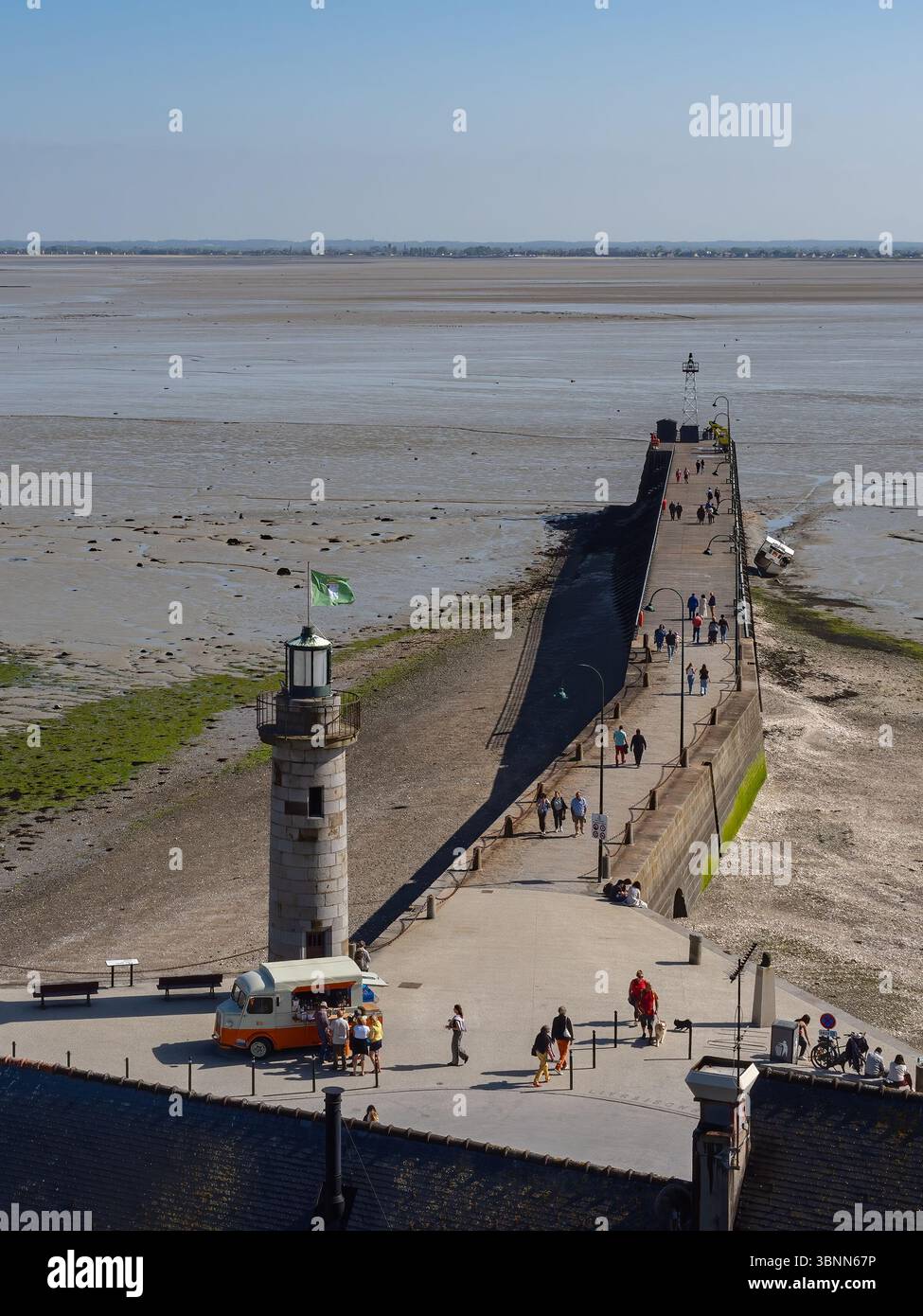 Cancale, Frankreich – 17. Mai 2025: Der Anleger und der Leuchtturm des Hafens Cancale in der Bretagne, bei Ebbe mit Fußgängern und einem Food truc Stockfoto