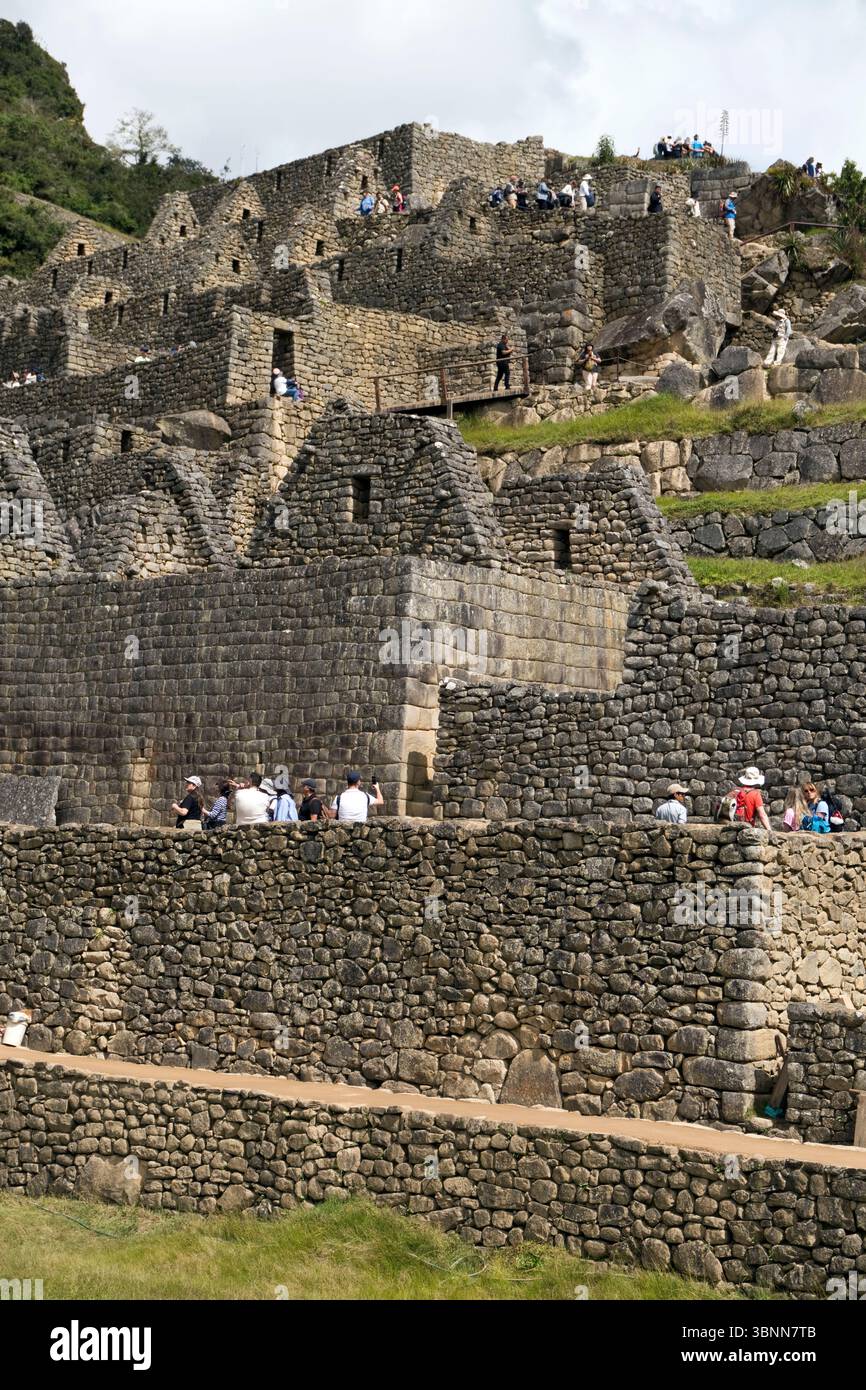Touristen in den Ruinen von Machu Picchu, der Inka-Zitadelle aus dem 15. Jahrhundert in Peru, die oft als „verlorene Stadt der Inka“ bezeichnet wird. Stockfoto