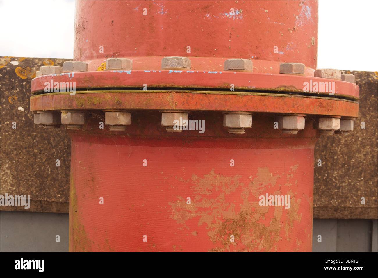 Nahaufnahme der Muttern und Bolzen eines roten Schleusenrohrs, die über die Mauer bei Breydon Water gehen, über die Schleusenebene, ins Breydon Water, Norfolk, England, Großbritannien Stockfoto