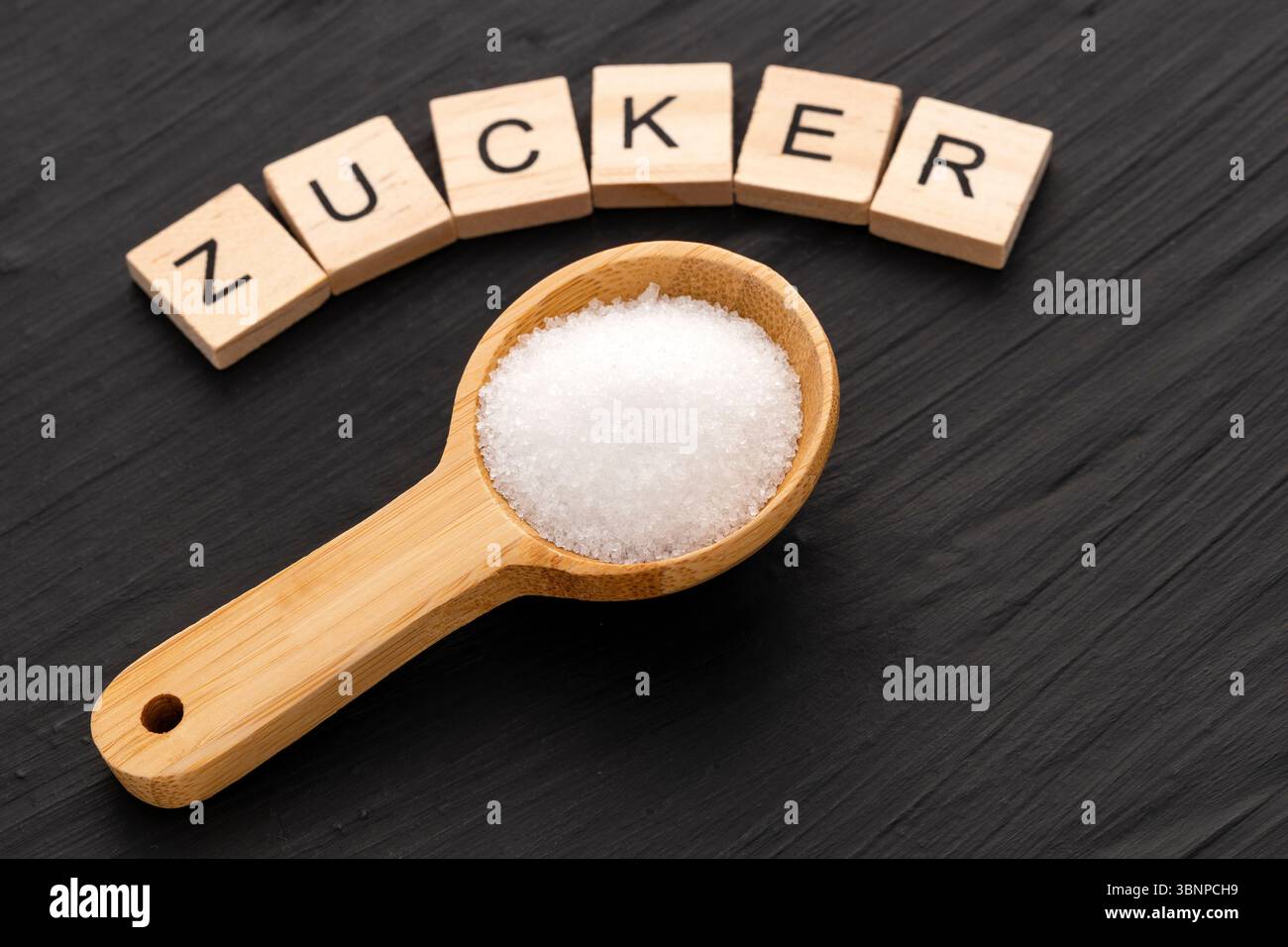 Raffinierter Weißzucker im Löffel - das Wort 'Zucker' ins Deutsche übersetzt Stockfoto