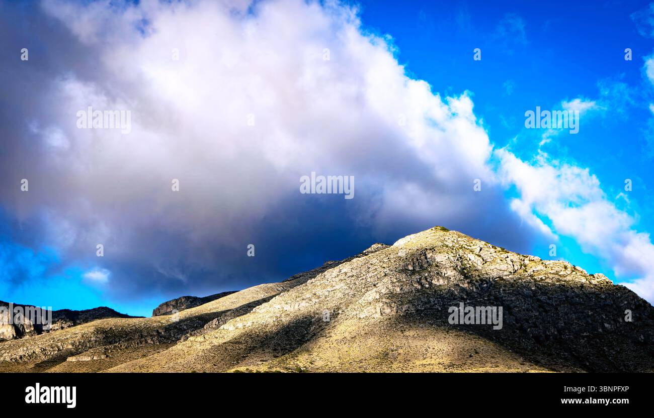 Dramatische Wolken brühen sich über den Guadalupe Mountains, während das Sonnenlicht durchbricht und Licht und Schatten über die zerklüfteten Bergrücken wirft. Stockfoto