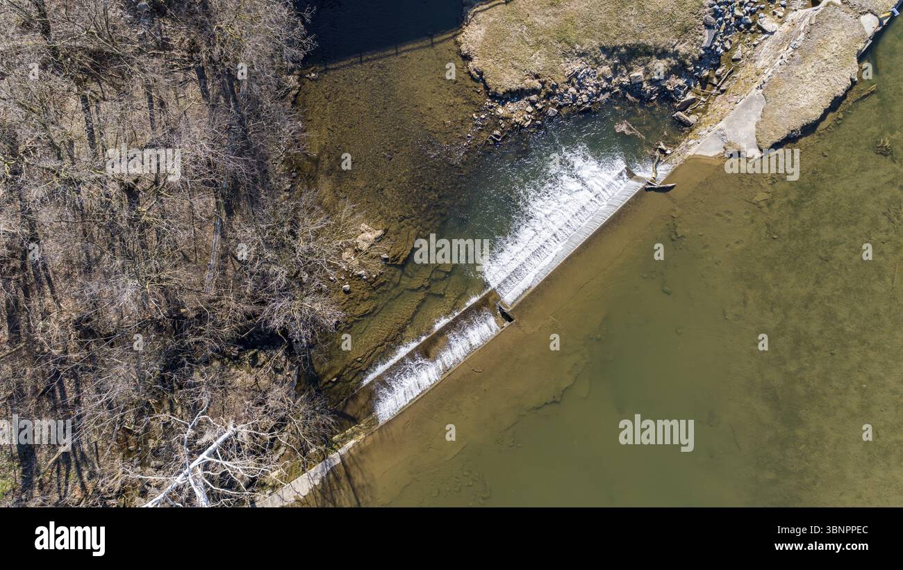 Eine abwärts gerichtete Sicht auf einen von einem Mann geschaffenen Wasserfall für eine Mühle an einem sonnigen Tag Stockfoto