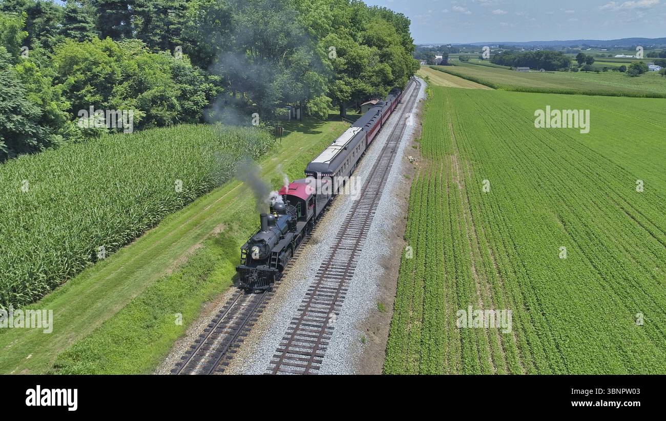 Luftaufnahme einer restaurierten antiken Dampfmaschine und Passagier Autos, die an einer kleinen Eisenbahnstation aufdampfen Ein Sommertag Stockfoto Luftaufnahme einer restaurierten antiken Dampfmaschine und Passagier Autos, die an einer kleinen Eisenbahnstation aufdampfen Ein Sommertag Stockfoto
