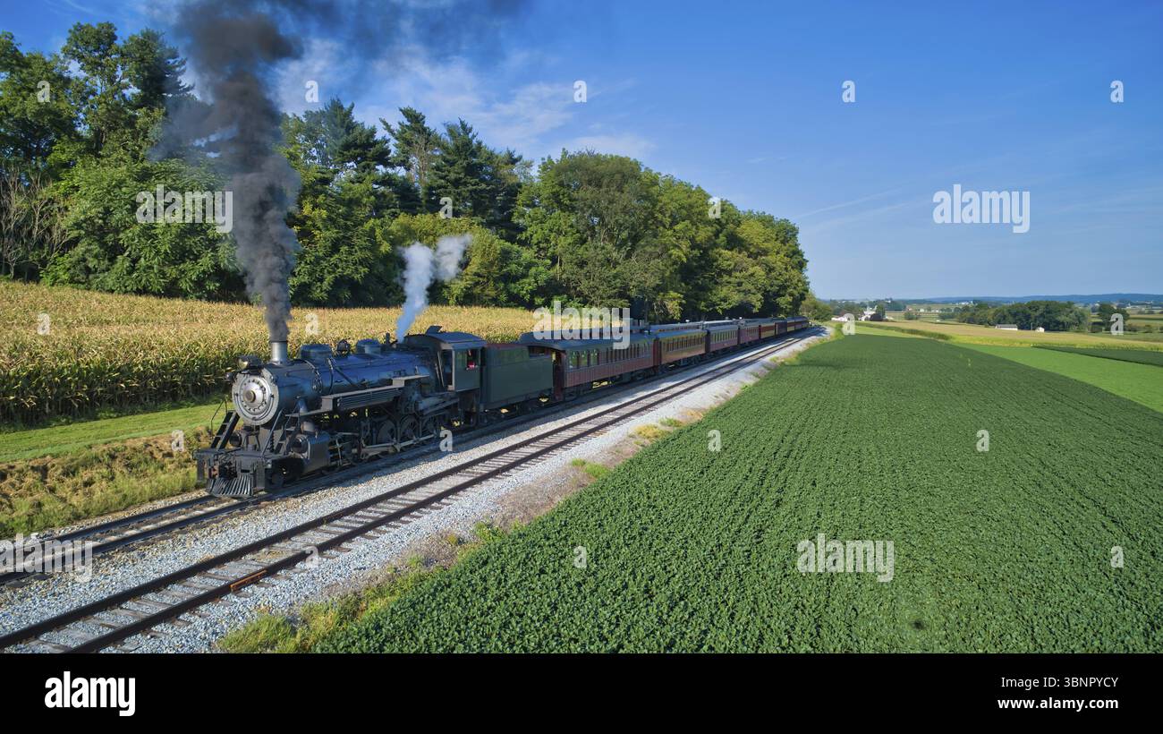 Luftaufnahme einer restaurierten antiken Dampfmaschine und Passagier Autos, die an einer kleinen Eisenbahnstation aufdampfen Ein Sommertag Stockfoto Luftaufnahme einer restaurierten antiken Dampfmaschine und Passagier Autos, die an einer kleinen Eisenbahnstation aufdampfen Ein Sommertag Stockfoto