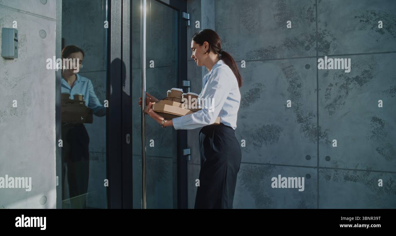 Liefermann übergibt Geschäftsfrau Zahlungsterminal nach erfolgreicher Pizzalieferung zum Bürogebäude. Frau hält Essen aus dem Restaurant, bezahlt für Bestellung kontaktlos mit Smartphone. Nahaufnahme. Stockfoto