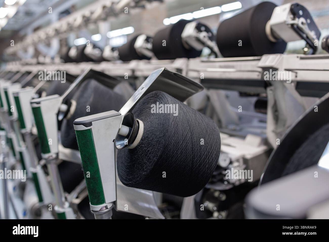 Nahaufnahme der Spinnlinie für die Garnherstellung mit automatisierten Textilmaschinen und industriellen Herstellungsprozessen Stockfoto