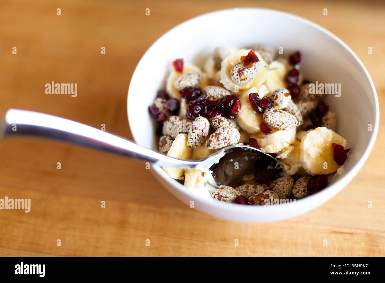 Ein Blick von oben auf eine gesunde Frühstücksschale mit Preiselbeeren, Mandeln, griechischem Joghurt und Bananen. Stockfoto