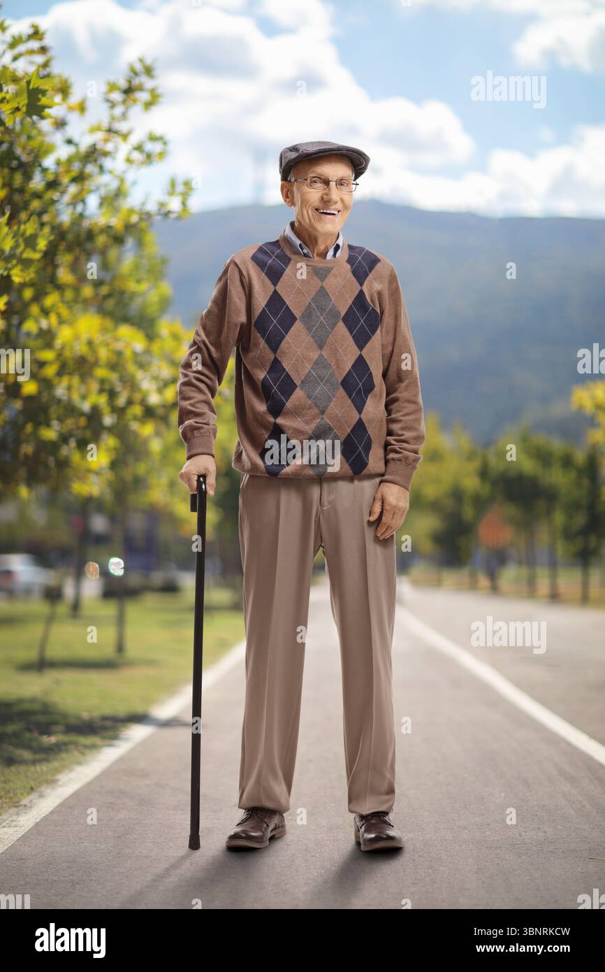 Porträt eines älteren Mannes, der mit einem Gehstock in einem Park steht Stockfoto