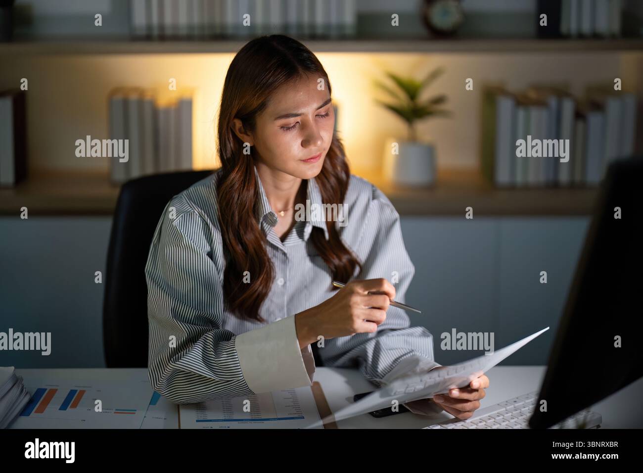 Analyse Der Späten Nacht. Junge Frau, die Dokumente überprüft, während sie spät arbeitet. Stockfoto
