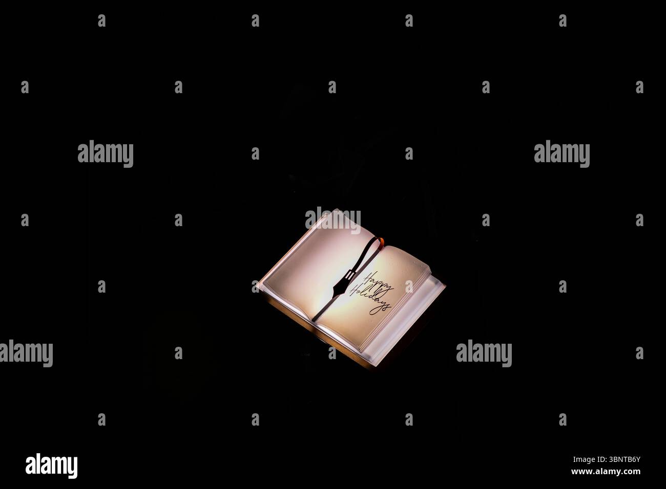 Beleuchtetes Buch mit Stift und Happy Holiday Text Stockfoto