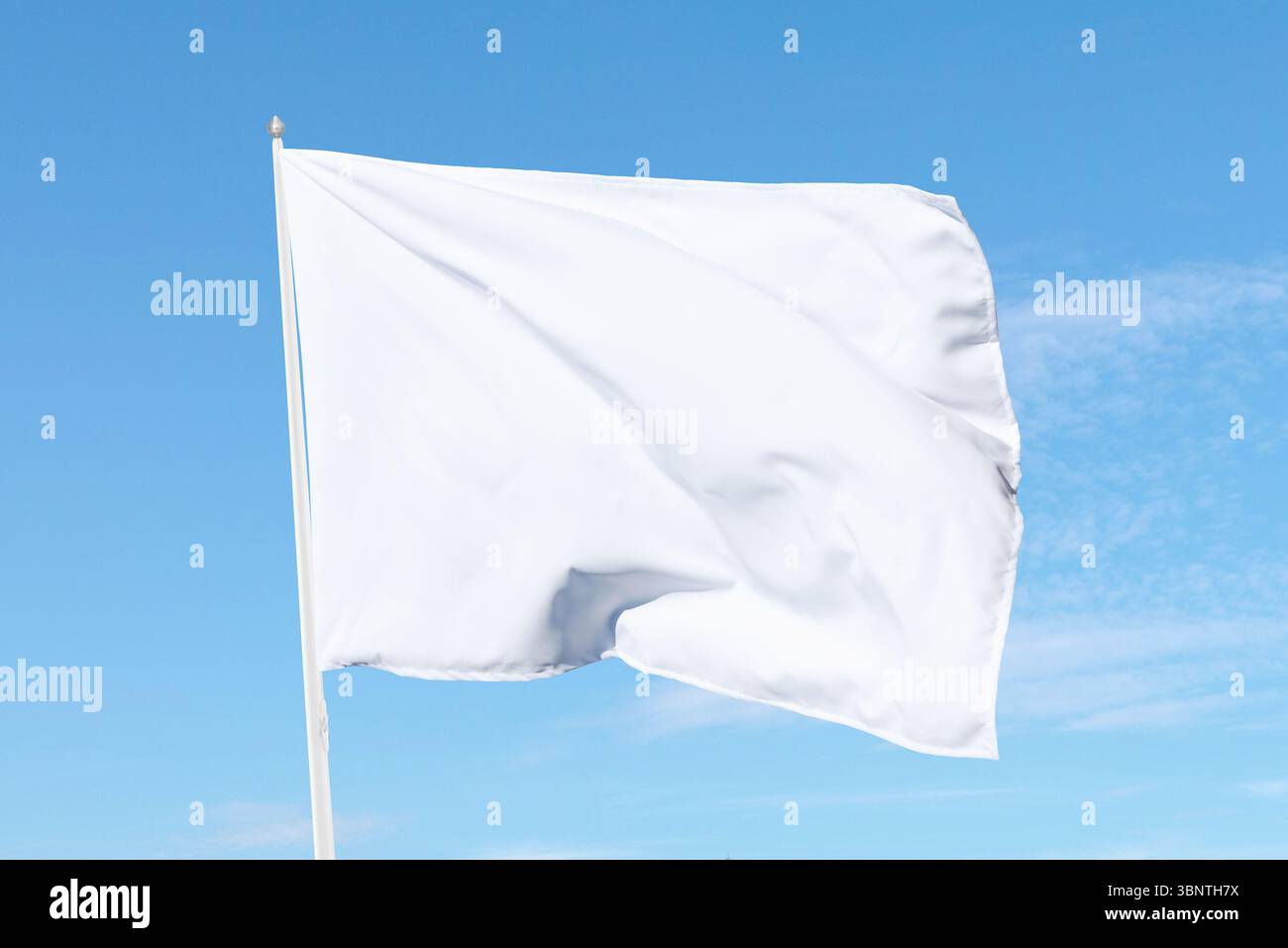 Weiße Flagge, die sanft auf einem Fahnenmast unter sonnigem Himmel weht, perfekt für Themen wie Neutralität, Ankündigungen oder klare Design-Ästhetik Stockfoto