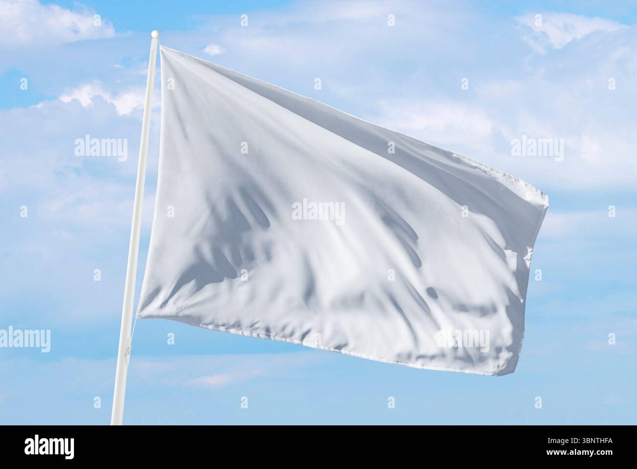 Weiße Flagge, die unter weichen Wolken winkt, perfekt für Themen wie Hingabe, ruhige Kommunikation oder neutrales Design in Web- oder Printprojekten Stockfoto