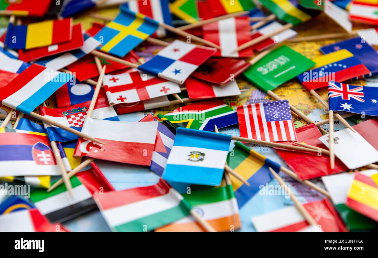 Nahaufnahme von verstreuten Länderflaggen auf einem Weltkartenhintergrund. Stockfoto