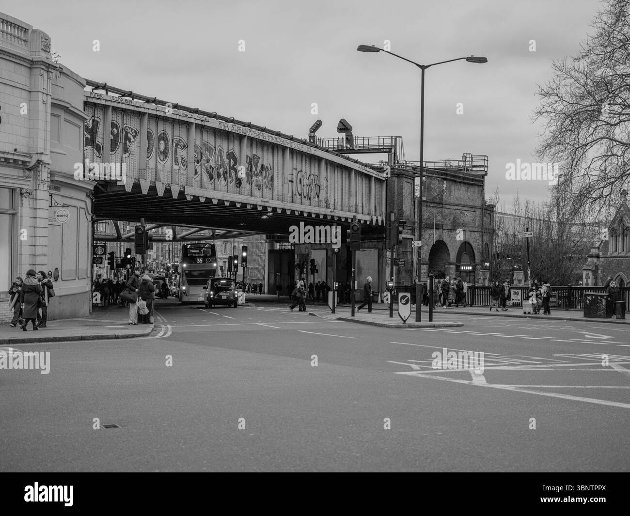 Vereinigtes Königreich, London, 11. Dezember 2024. Ein Blick auf die schwarz-weiße Straße unter Eisenbahnbögen in der Nähe eines Marktes in East London, der den urbanen Text der Stadt zeigt Stockfoto