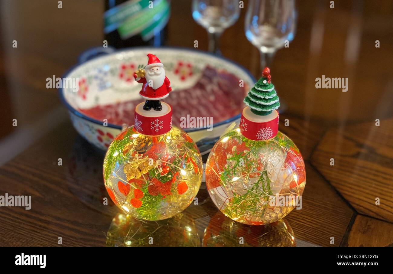 Glühende Weihnachtskugeln, reflektierend auf einem Tisch Stockfoto