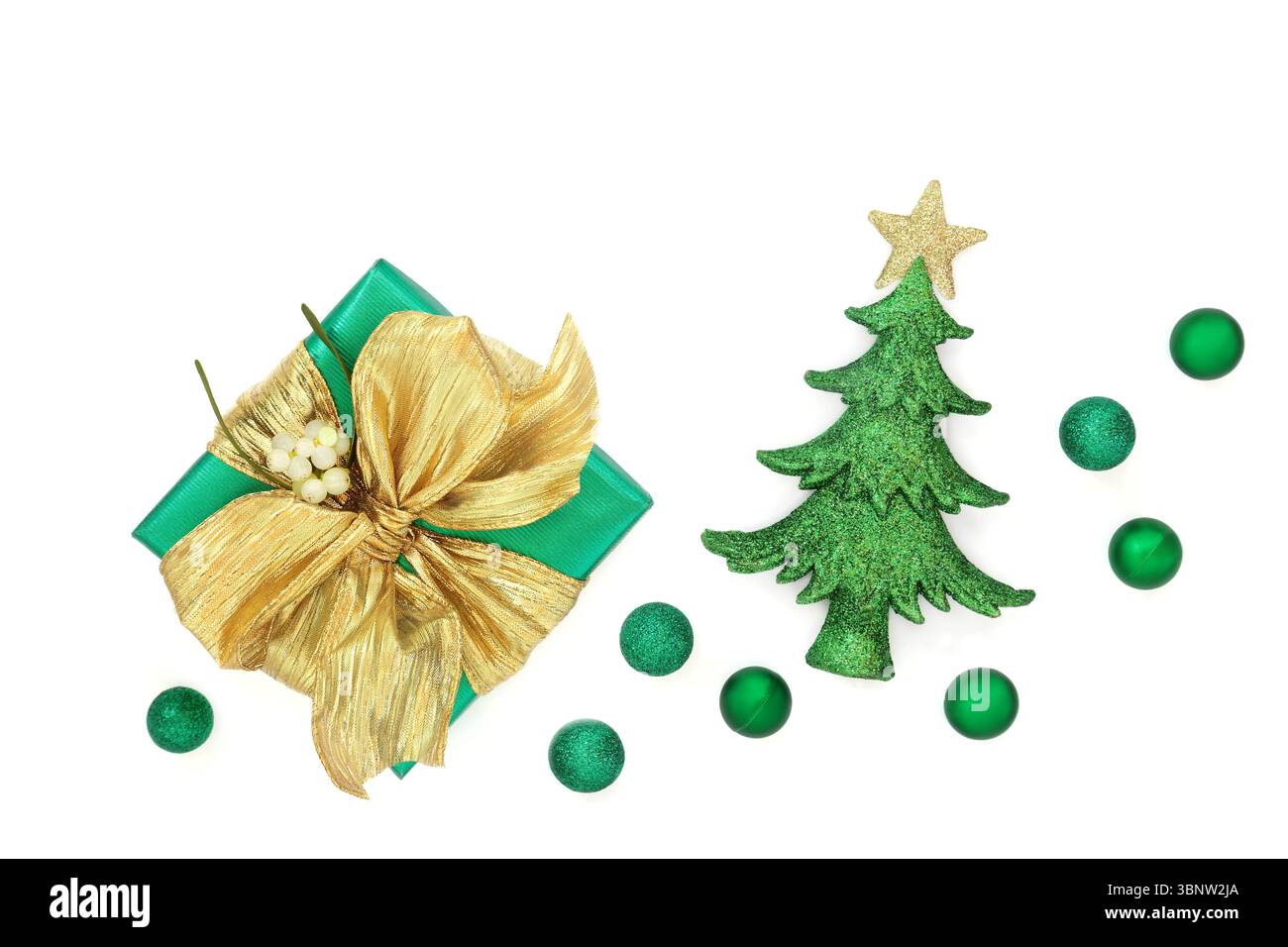Grüne Geschenkbox, goldene Schleife, Mistel, Weihnachtsbaum, Kugelkugel Dekorationen auf weißem Hintergrund. Festliche traditionelle Feiertagssymbole Stockfoto