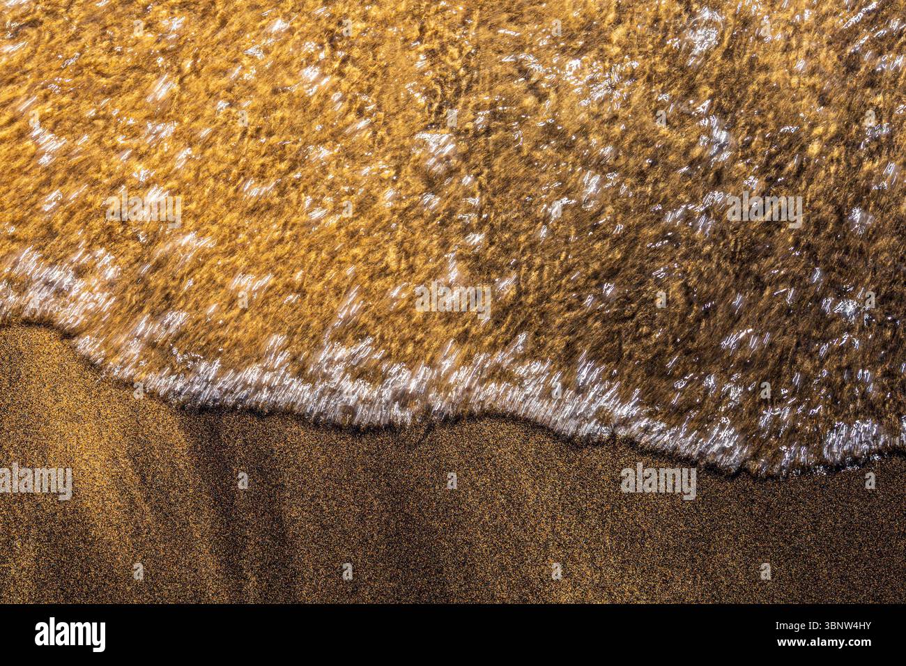 Kristallklares Wasser wäscht sanft goldenen Sand am Ufer des Lake Tahoe und kreiert wunderschöne Muster Stockfoto