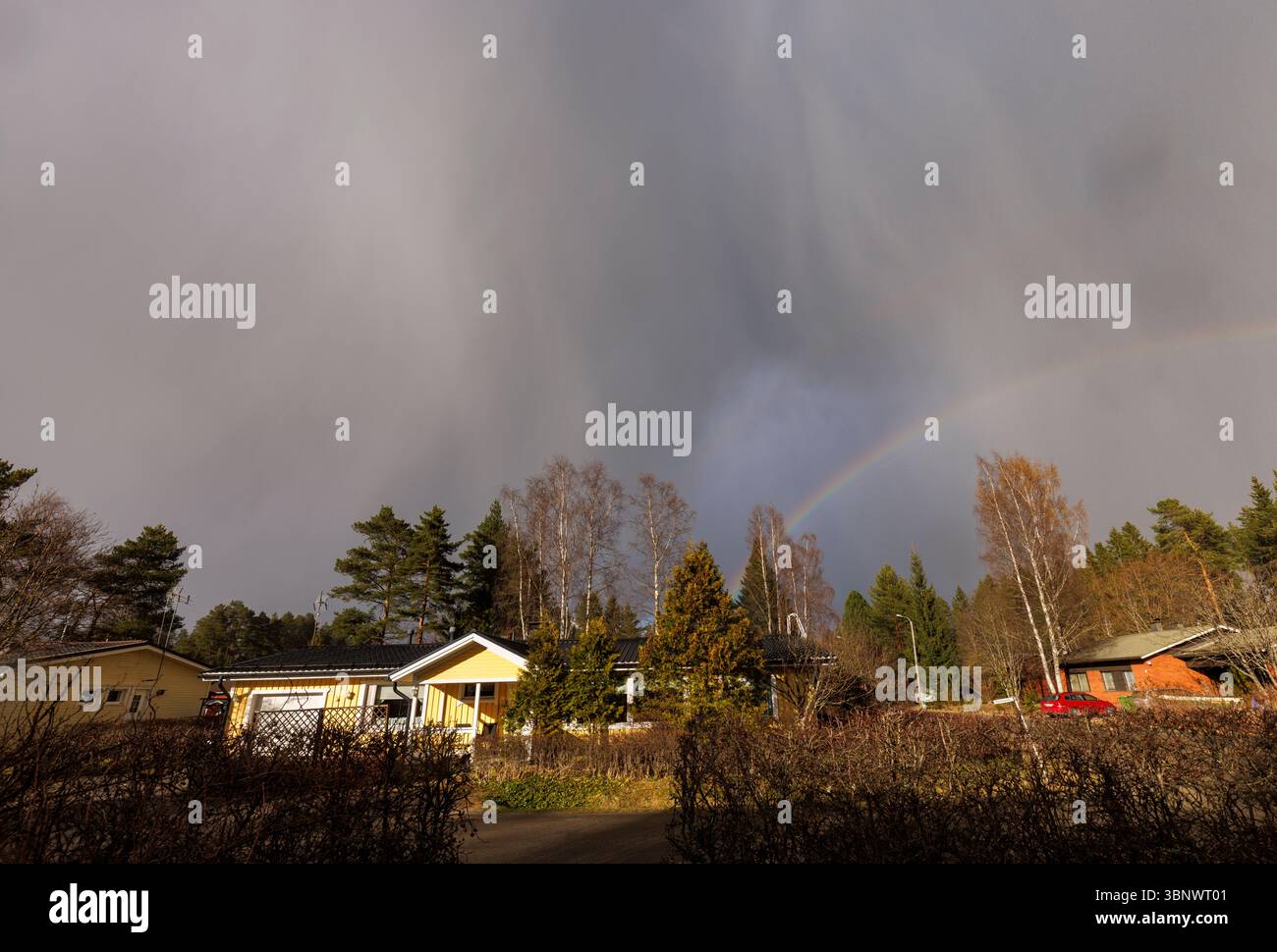 Regenwolken und Regenbogen über finnischem Wohngebiet, Finnland Stockfoto