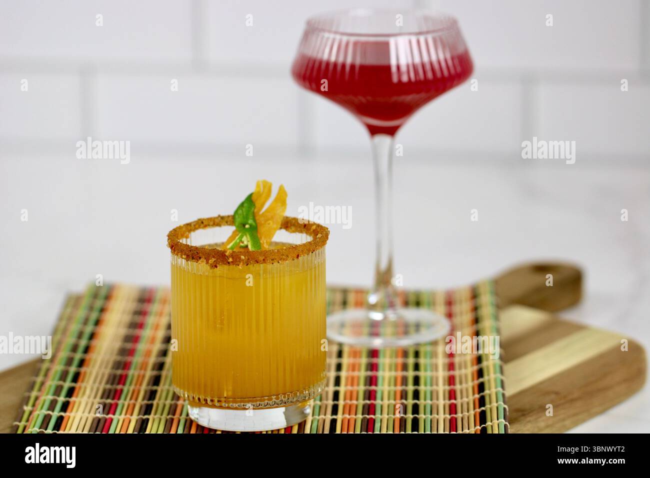 Lebendige Mocktails auf farbenfroher Matte - Mango- und Beerengetränke mit Garnelen- und Glaswaren-Design Stockfoto