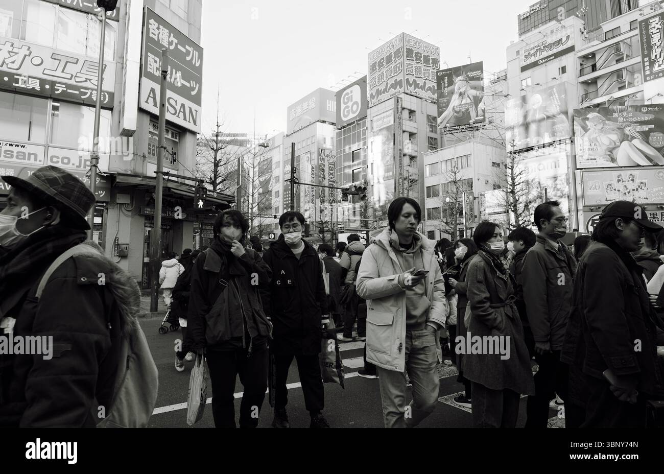 Überqueren Sie die geschäftige Kreuzung Akihabara, umgeben von farbenfrohen Anime-Plakaten und Neonschildern Stockfoto